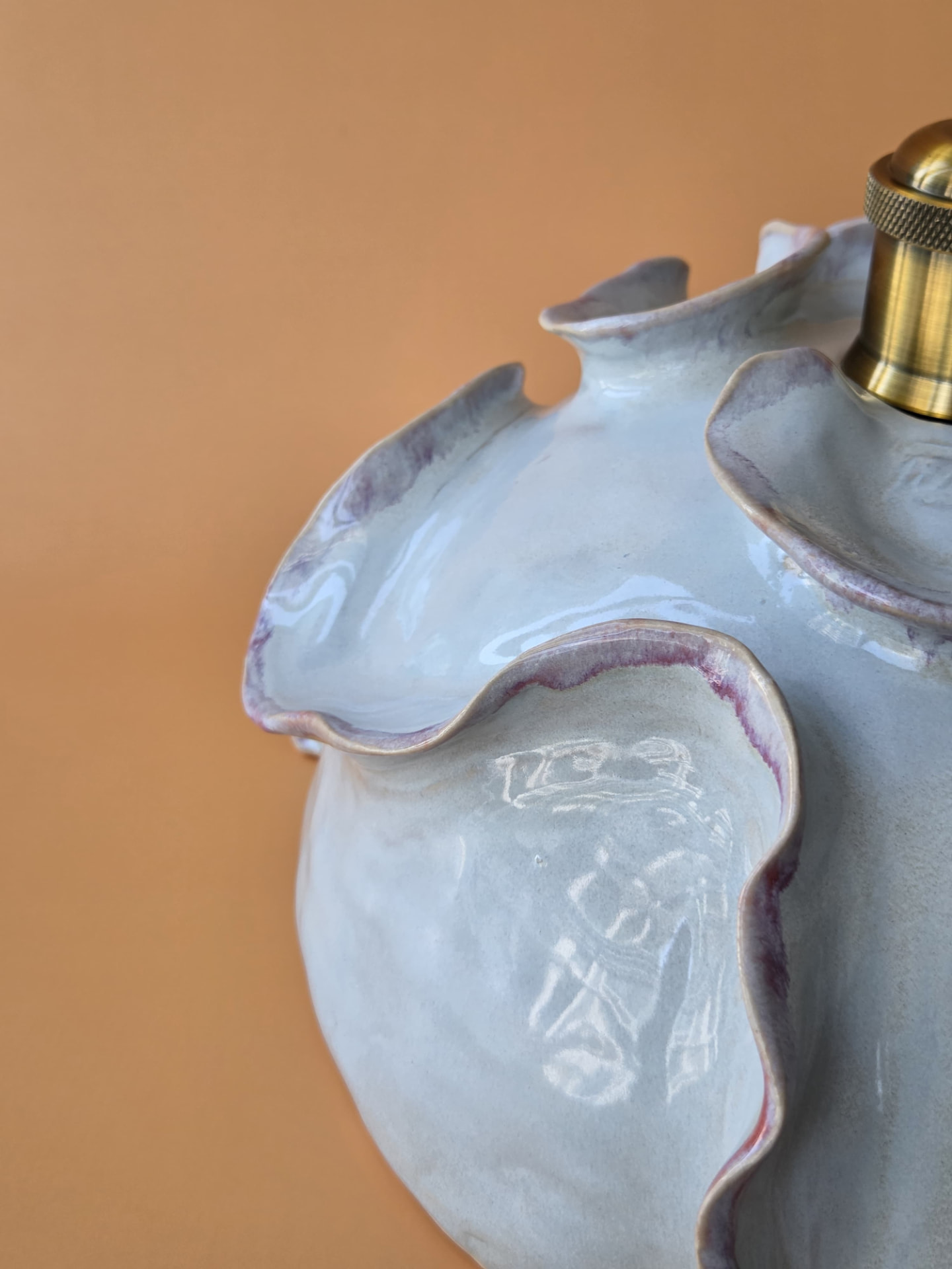 Detail of Coralline's layered ceramic form with soft purple tones against a warm backdrop