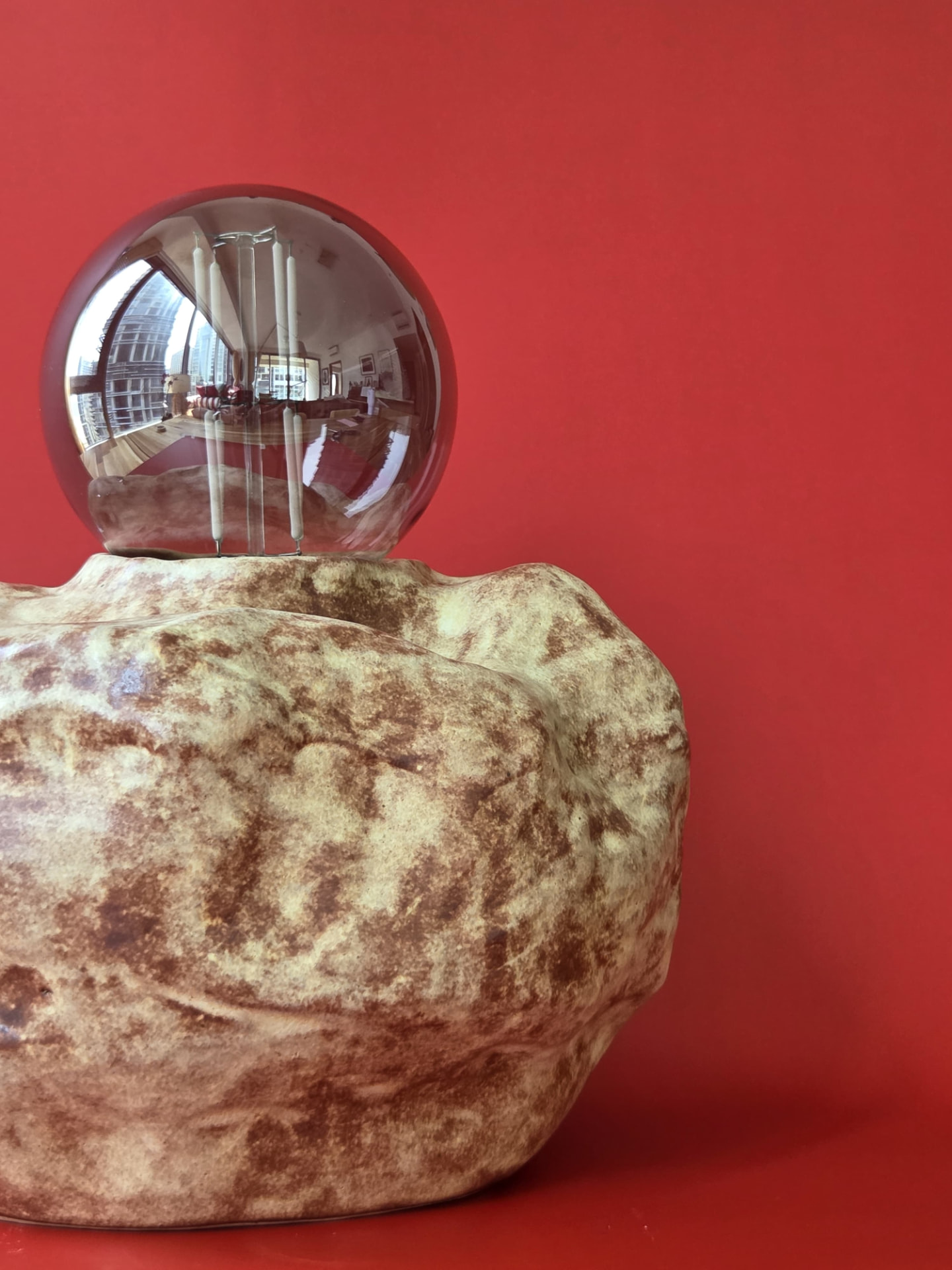 Close view of Erratic's irregular, weathered surface and smoked glass globe