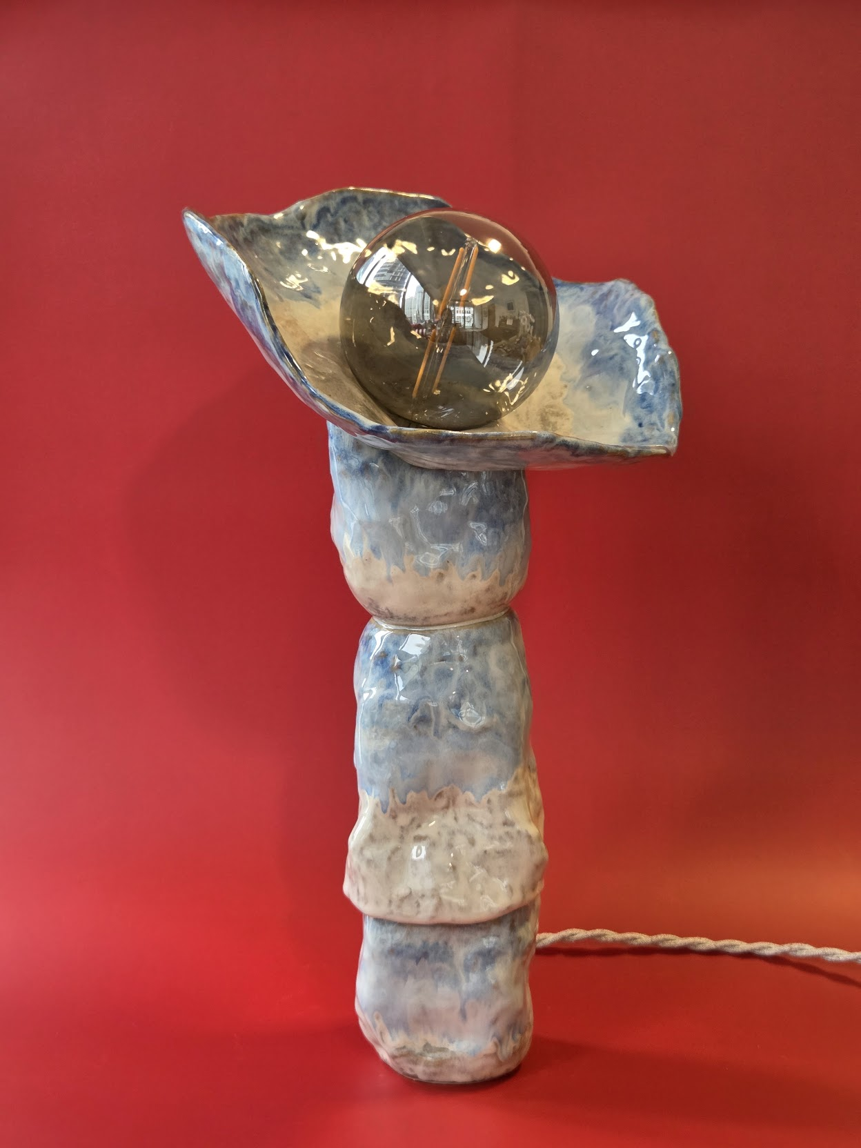 Riffle stoneware table lamp seen from the side, showing its stacked shifting forms and smoked glass globe