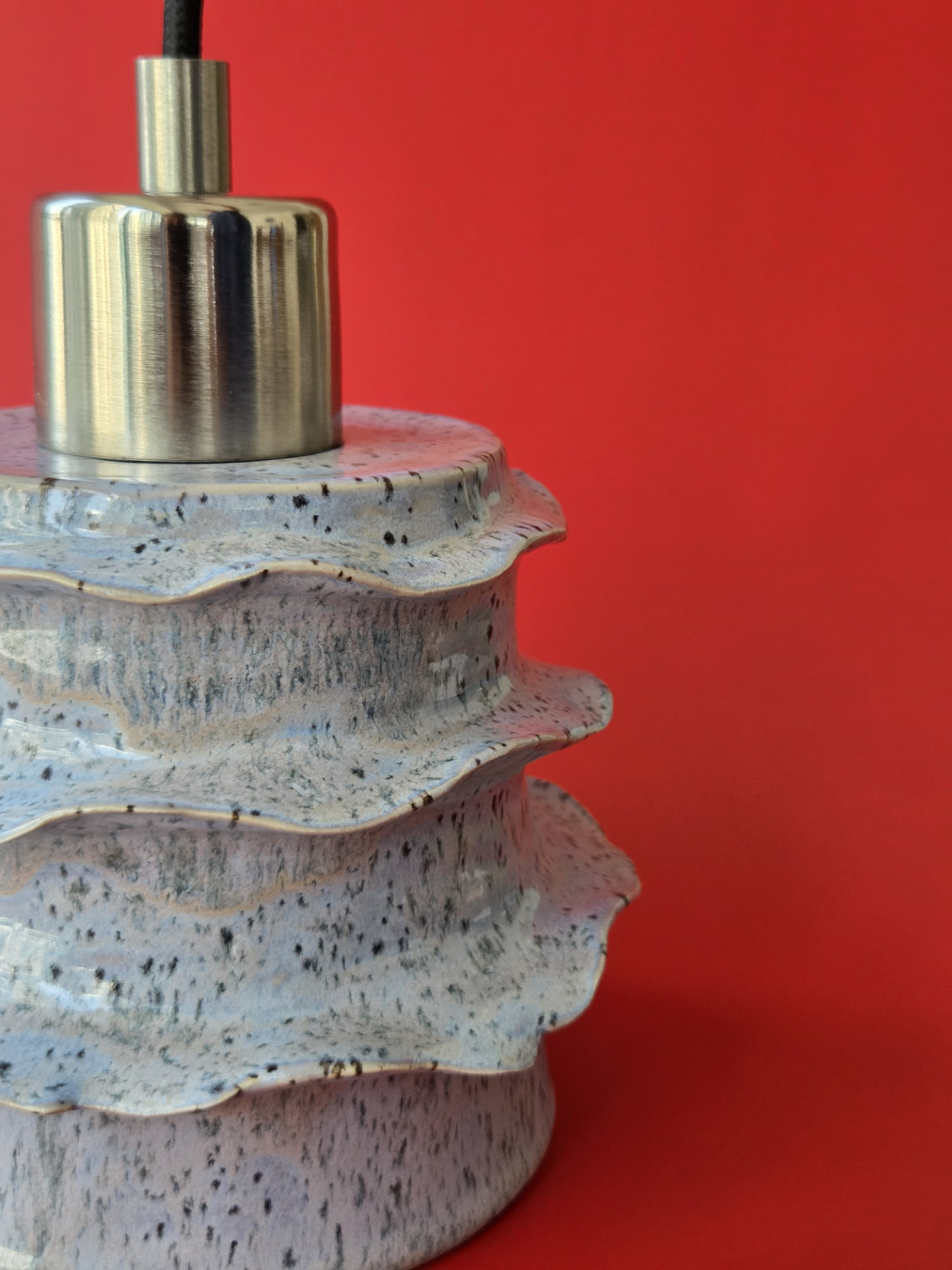 Close detail of Strata's tiered stoneware form, irregular rim edges and nickel furnishing