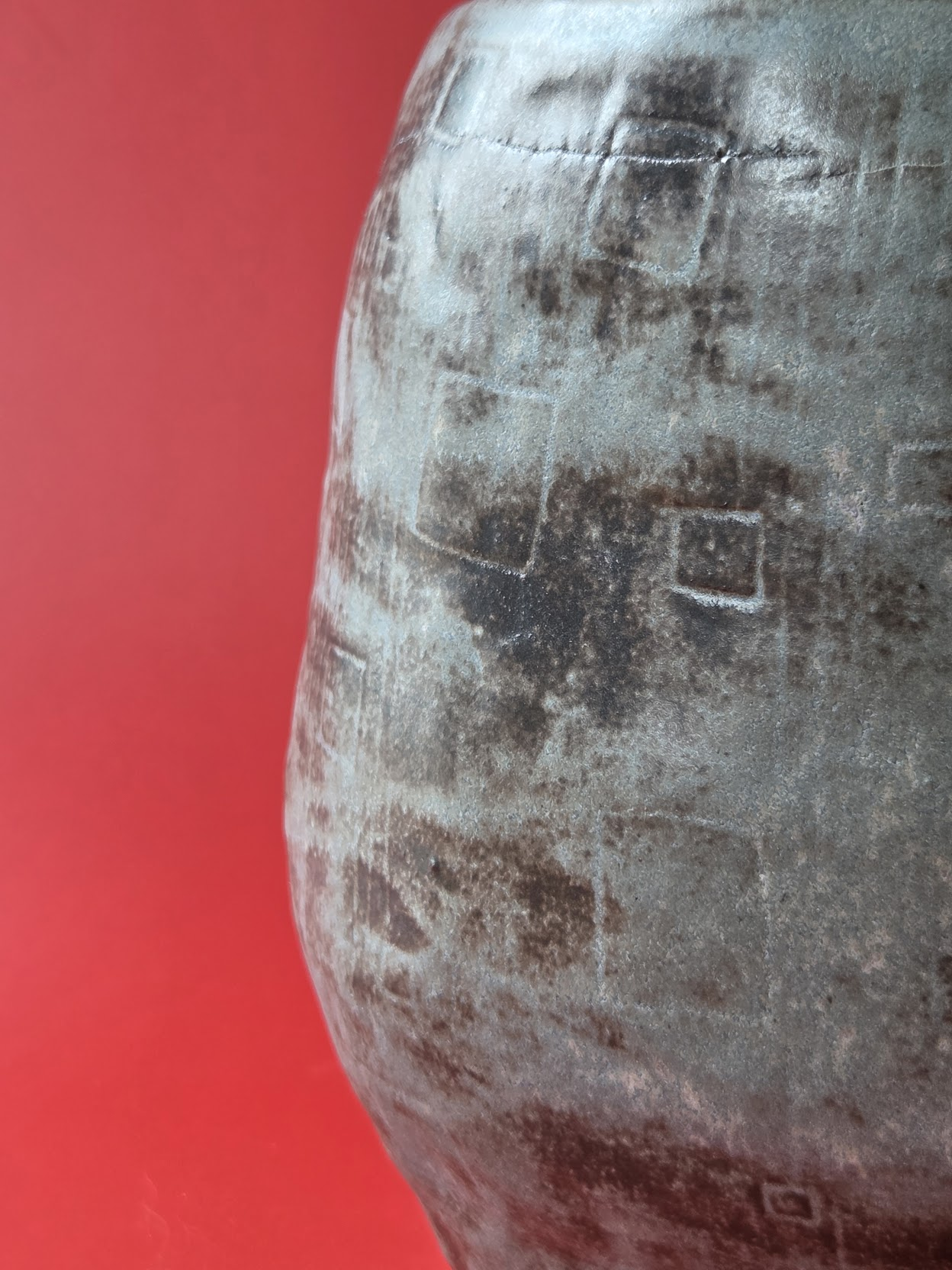 Close detail of Tarn's dark, weathered stoneware surface and impressed geometric marks