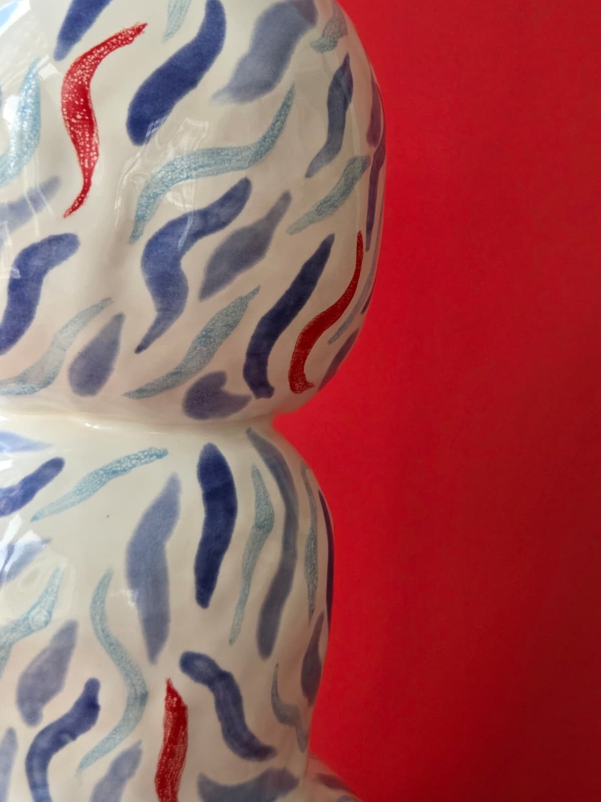 Close detail of Drift's hand-painted blue and red brushmarks across two stacked ceramic forms