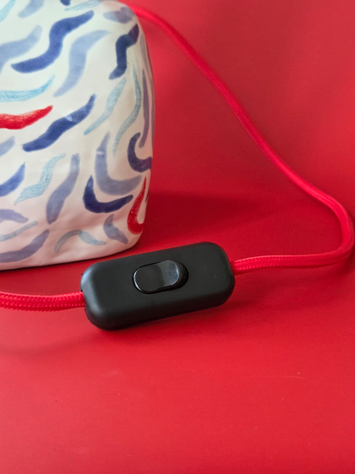 Base of Drift with its red fabric cord and inline switch on a red surface